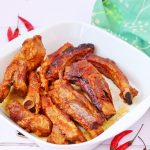 Slow cooked barbecue ribs in a white bowl with some red chillies on the side