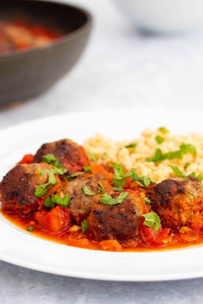Mint and lamb meatballs on a plate with a pan in the background