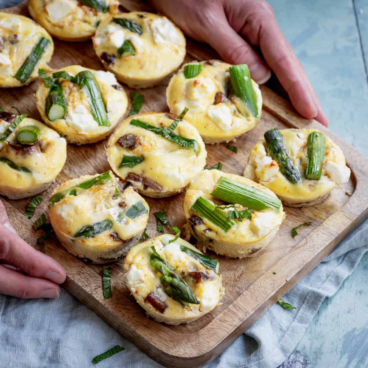 Mini frittatas on a board with asparagus and mushrooms