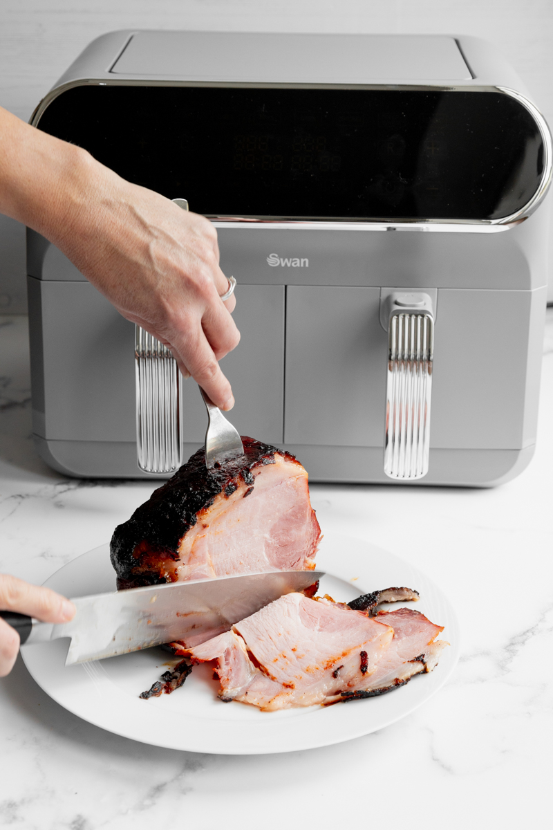 Slicing into the gochujang ham with the air fryer in the background